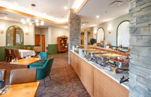 Enjoy a meal at our dining area, featuring a buffet with various food options and comfortable seating.