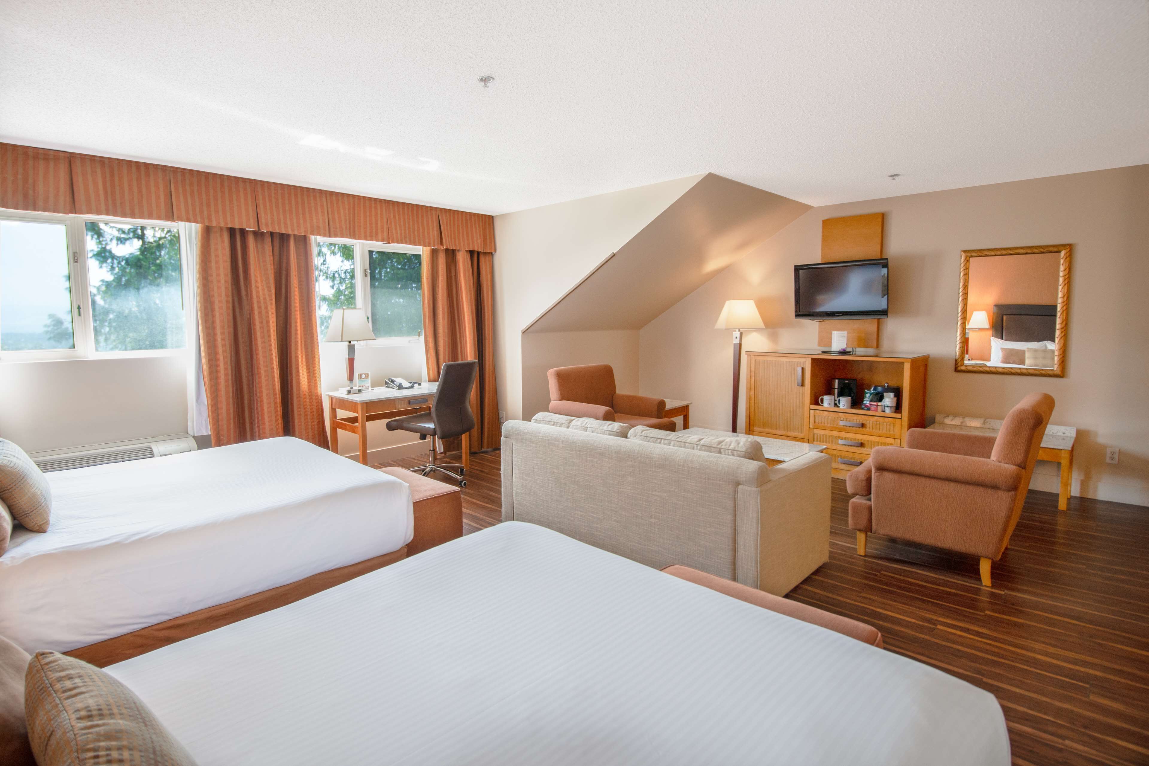 A hotel room with two beds, a desk, a TV, and a sofa.