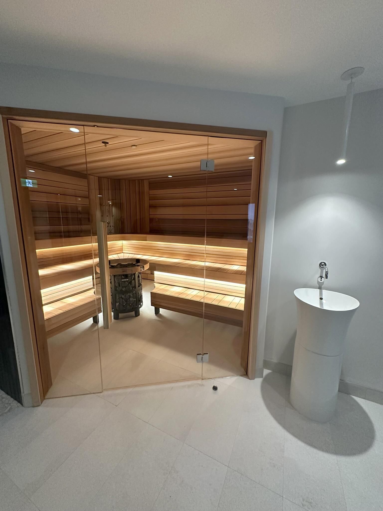 Un sauna équipé de bancs, d’un poêle en pierre et d’un lavabo.