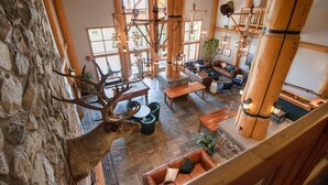 A rustic interior with stone walls, wooden furniture, and a large antler decoration.