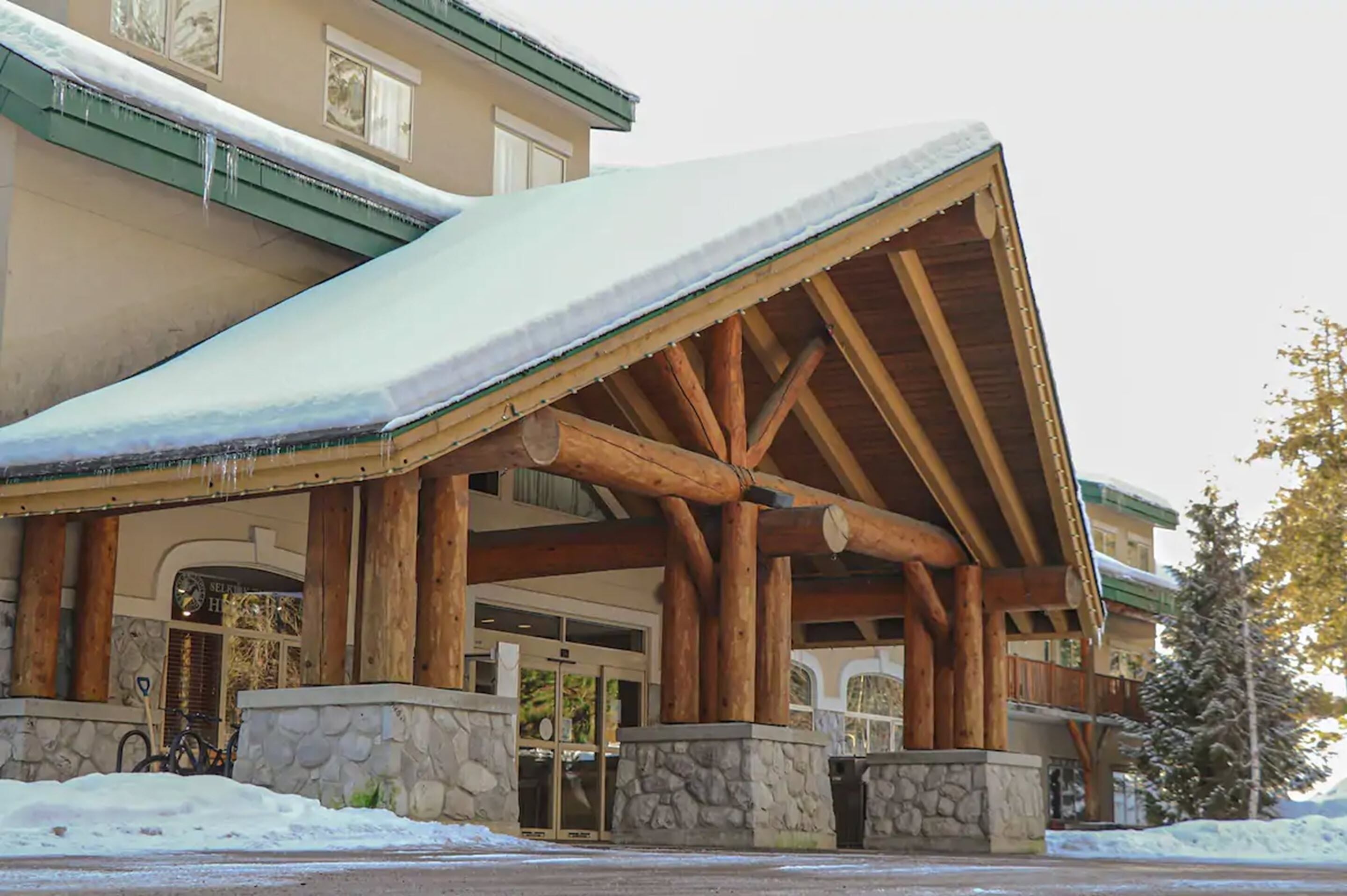A lodge with a snow-covered roof and stone pillars.