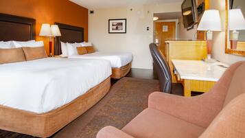 A hotel room with a double bed, a desk, a chair, a television, and a mirror.