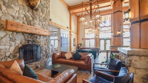 A cozy interior with stone walls, leather sofas, a fireplace, and wooden beams.