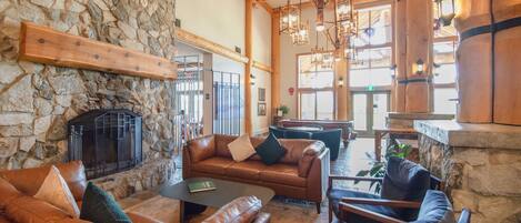 A cozy interior with stone walls, leather sofas, a fireplace, and wooden beams.