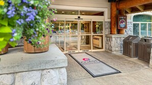 A hotel entrance with a glass door, a stone wall, and a wooden ceiling.
