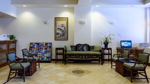 A lobby with a sofa, chairs, a bulletin board, and a television. - SW Hotel – No Resort Fee (San Francisco)