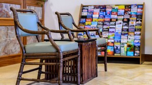 Two wooden chairs with cushioned seats and backs, positioned in front of a bulletin board filled with colorful pamphlets. - SW Hotel – No Resort Fee (San Francisco)