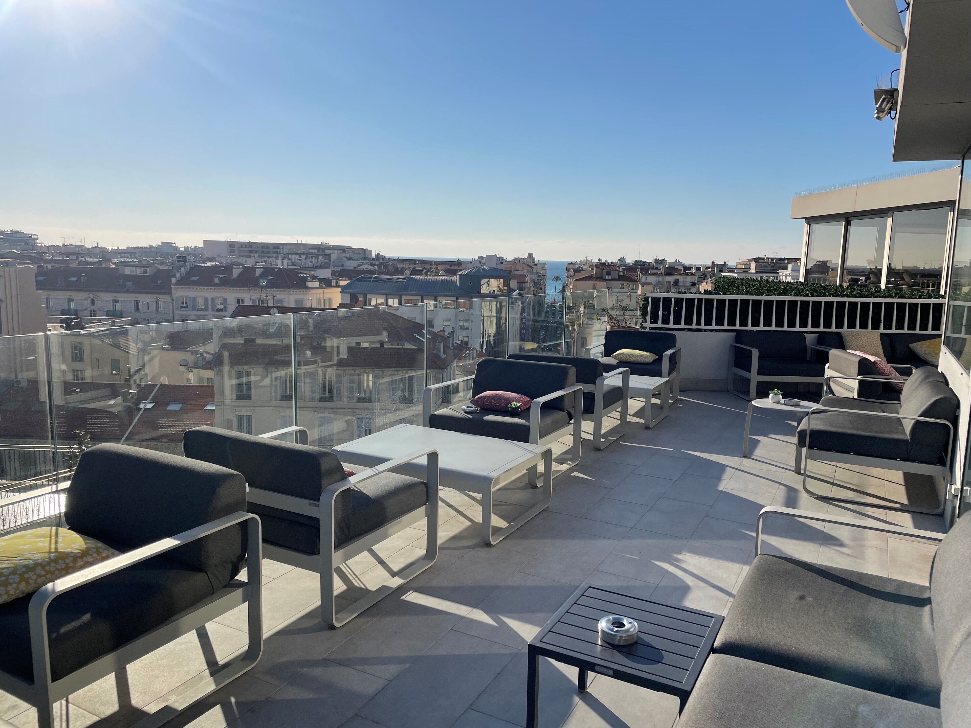 Una terraza en la azotea con mobiliario exterior, una mesita y vistas a la ciudad.