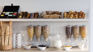 Een ontbijtbuffet met diverse soorten eten, zoals brood, gebak en cornflakes.