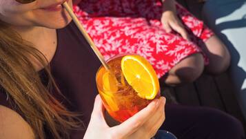 Eine Person hält ein Glas mit einem Strohhalm und einem Orangenscheibchen.