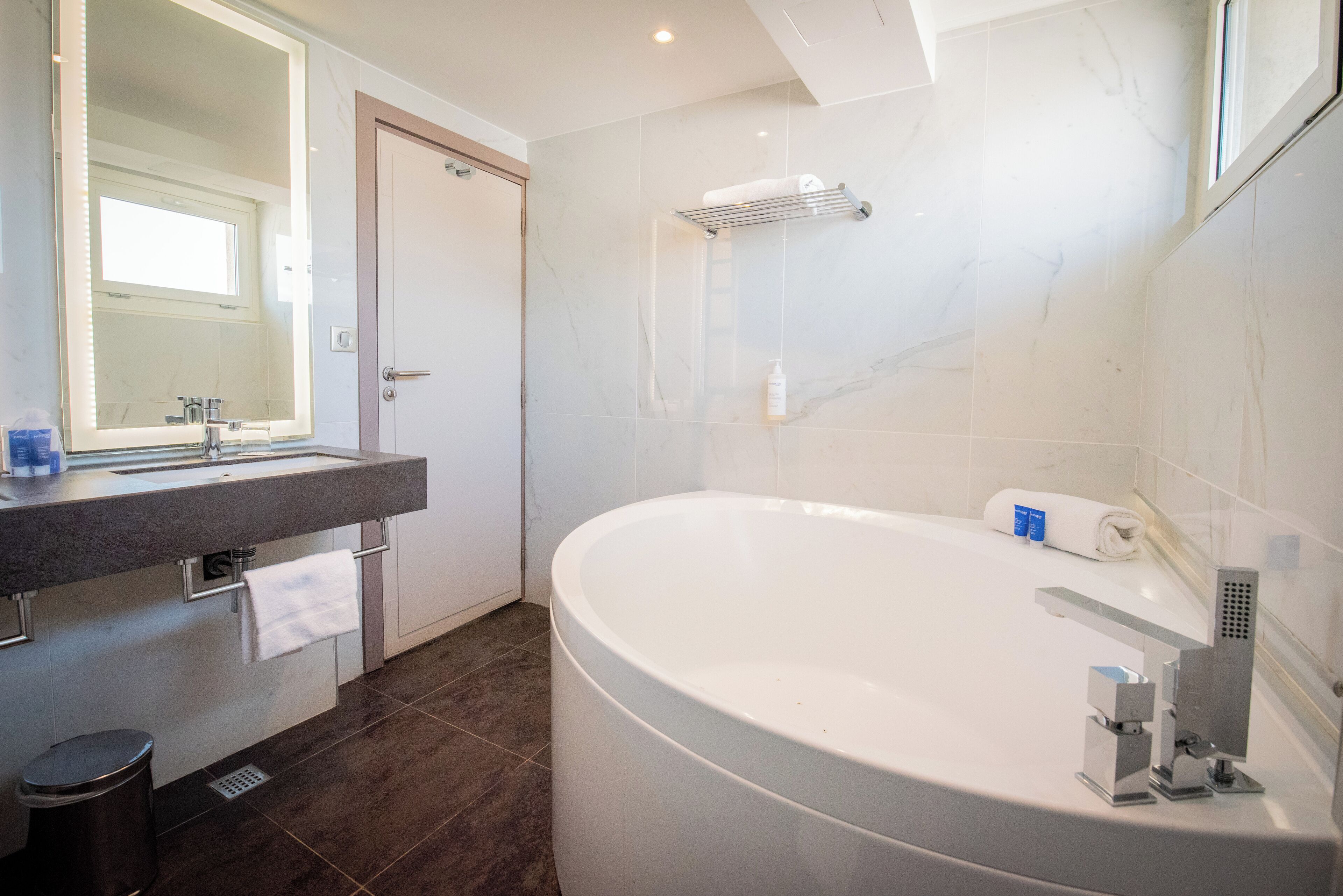 Un bany modern amb una banyera gran, un lavabo amb mirall i un penjador de tovalloles.