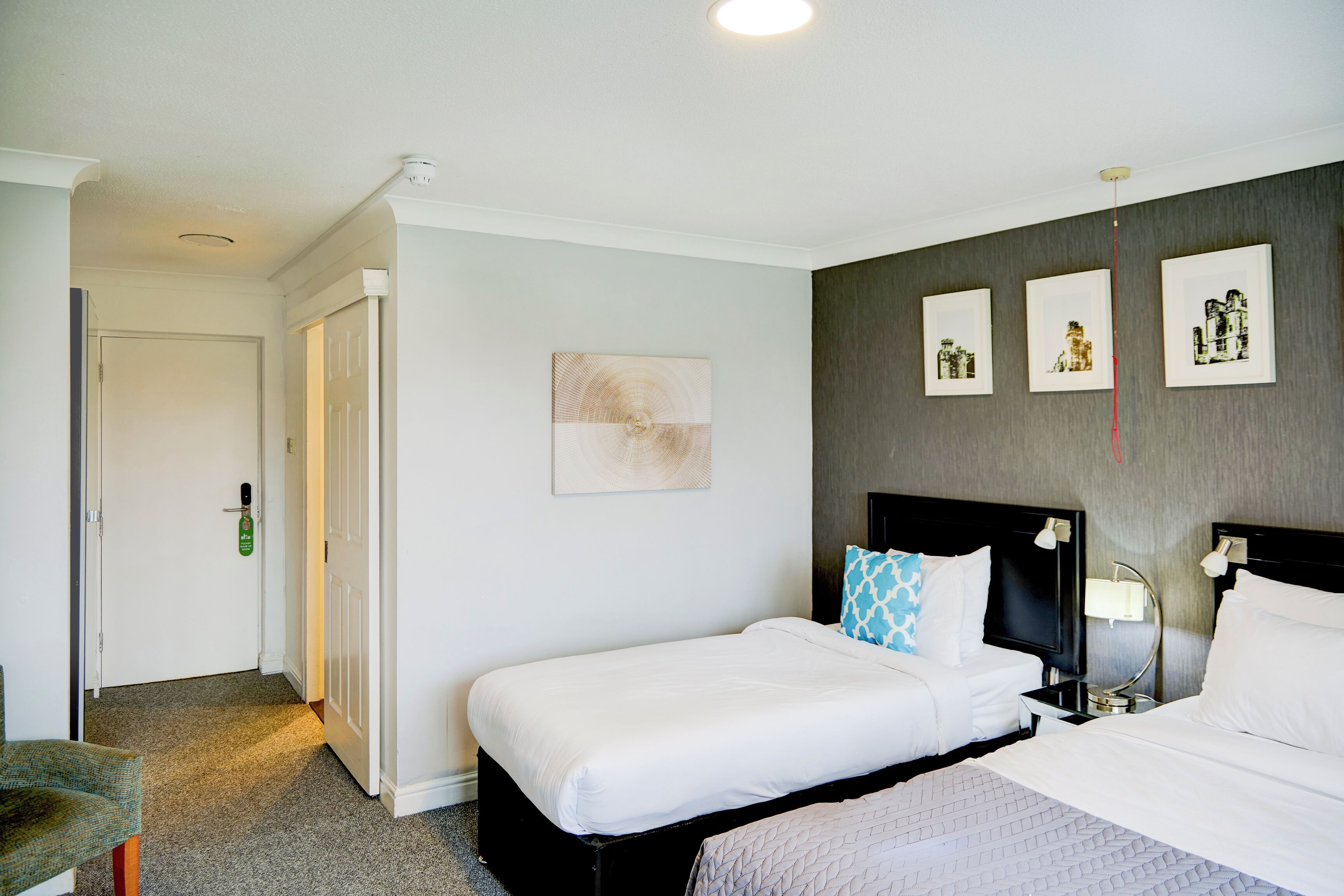 A hotel room with a bed, a bedside table, a chair, and a door.
