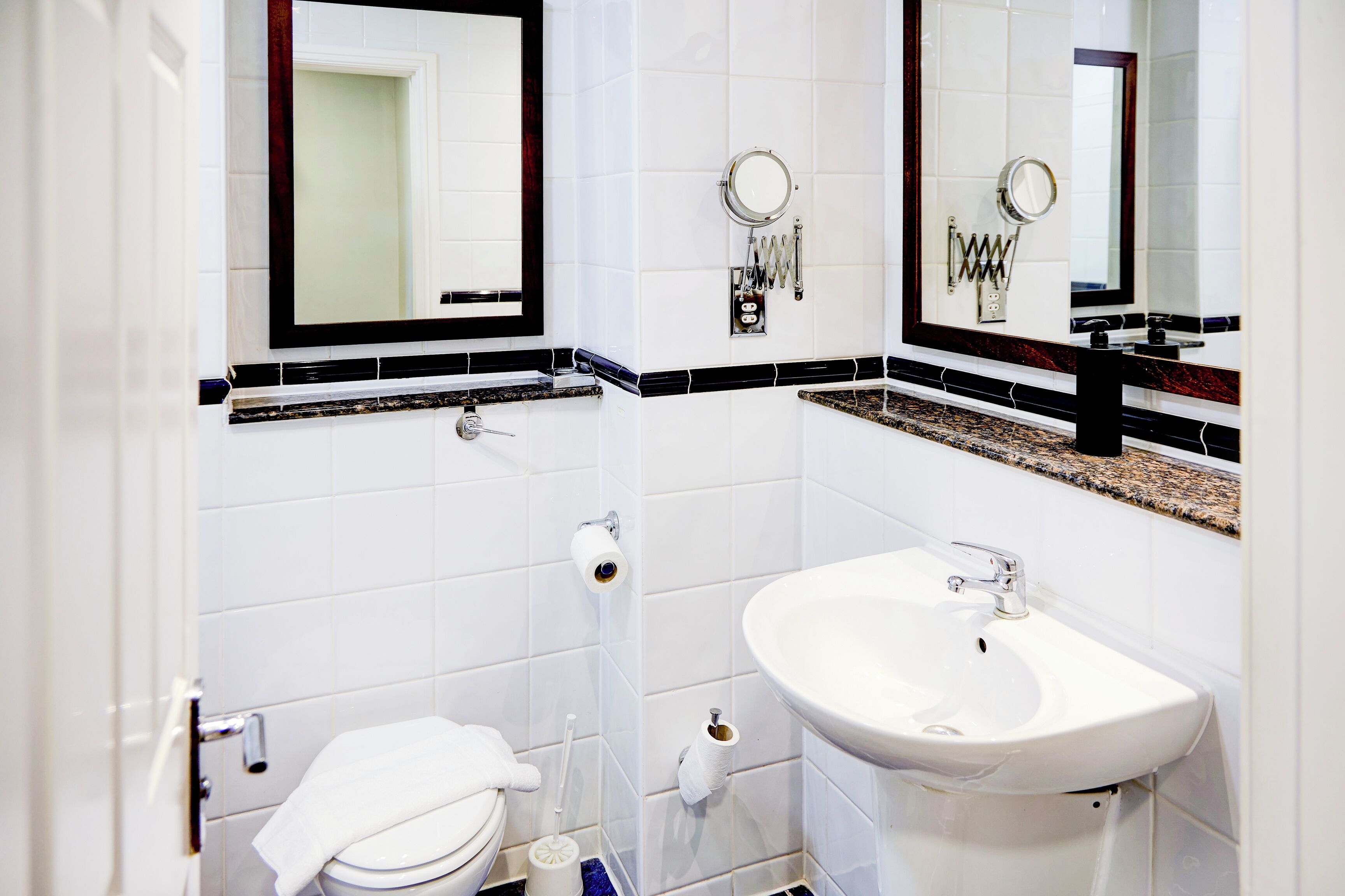 A bathroom with a white toilet, a sink, and two mirrors.