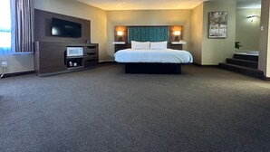 A hotel room with a bed, a TV, a microwave, a desk, and a staircase leading to another room. - Travelodge by Wyndham Amherst (West Amherst)
