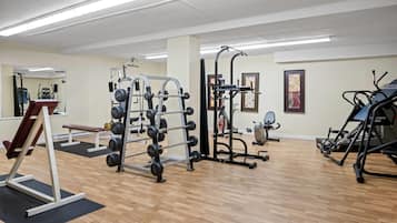 A gym with various exercise equipment, including a squat rack, weight bench, and cardio machines.
