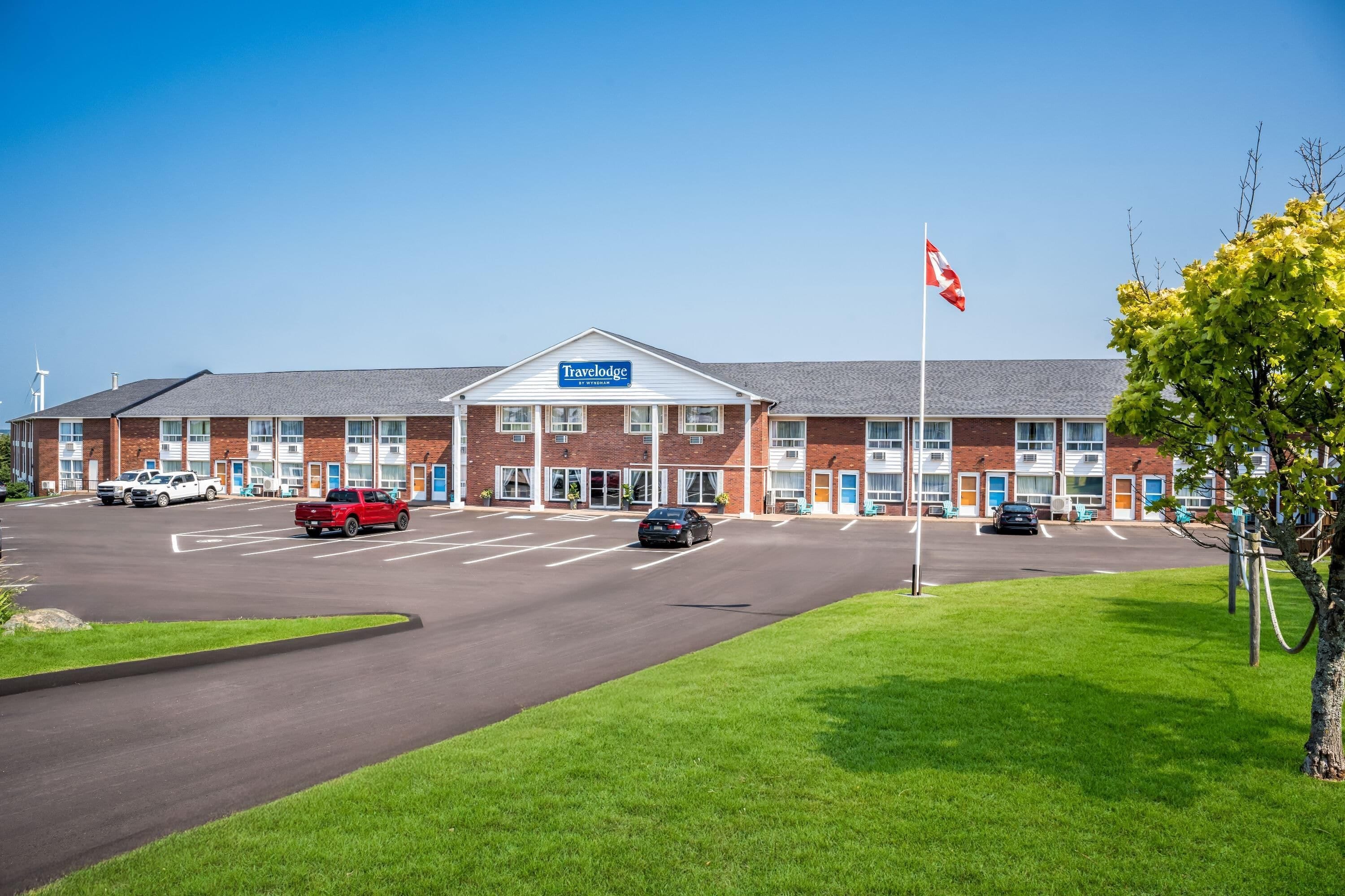 Ein Travelodge Hotel mit Backsteinfassade, Parkplatz und einer Flagge.