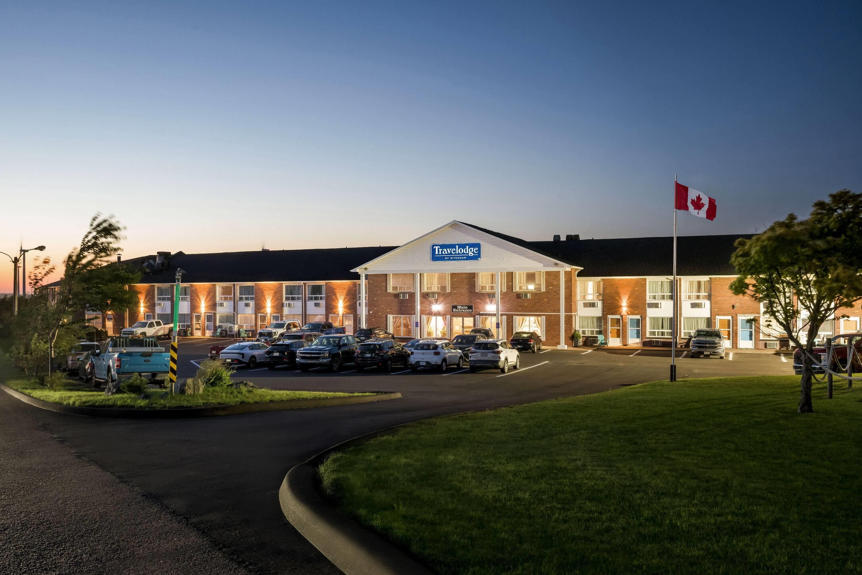 A Travelodge hotel with a main entrance, parking lot, and a Canadian flag.