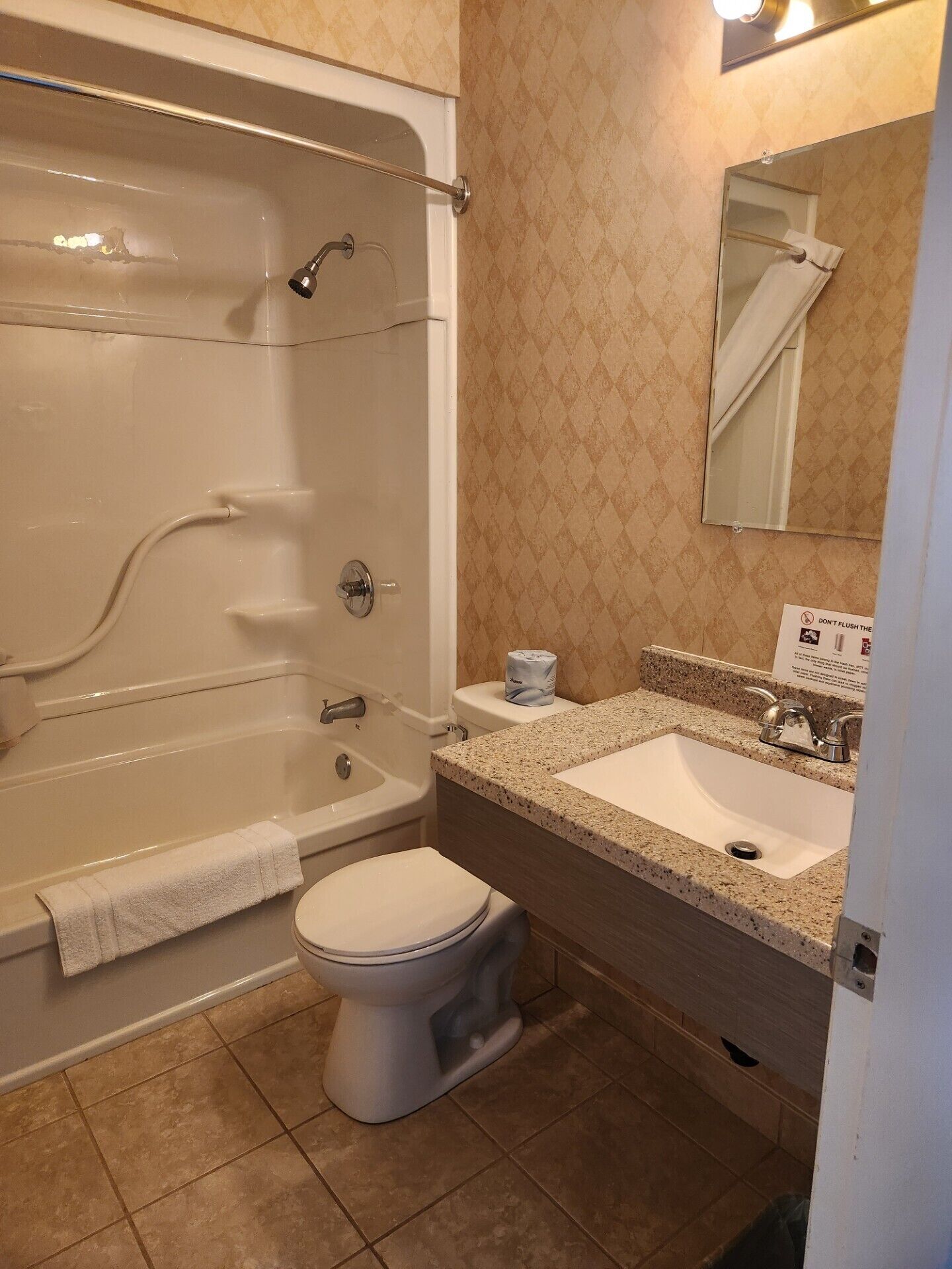 Een badkamer met een bad, toilet, wastafel en spiegel.