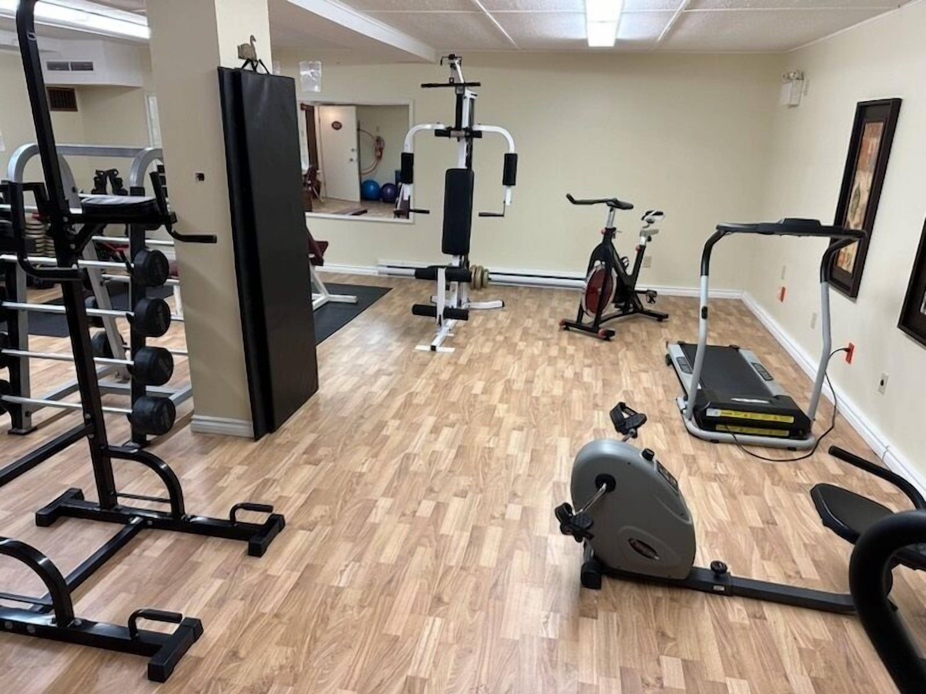 A gym with various exercise equipment including a treadmill, stationary bike, and weight machines.