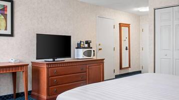 Une chambre d’hôtel équipée d’un lit, d’une télévision, d’un four à micro-ondes, d’une machine à café et d’une commode.