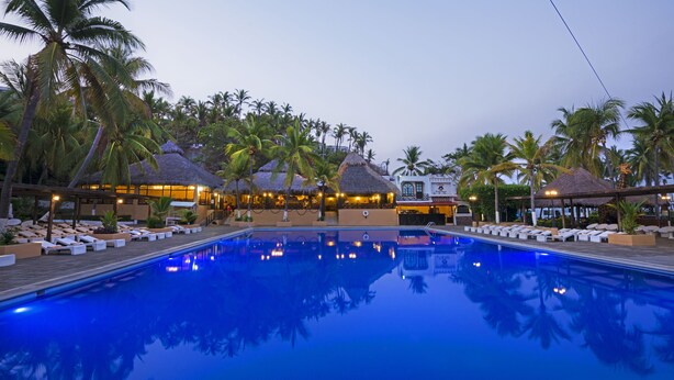 A pool area with lounge chairs and thatched-roof structures, surrounded by palm trees. - Vista Playa de Oro Manzanillo (Manzanillo)
