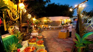 An outdoor dining area with tables set for a meal, surrounded by potted plants and decorative lighting. - Vista Playa de Oro Manzanillo (Manzanillo)