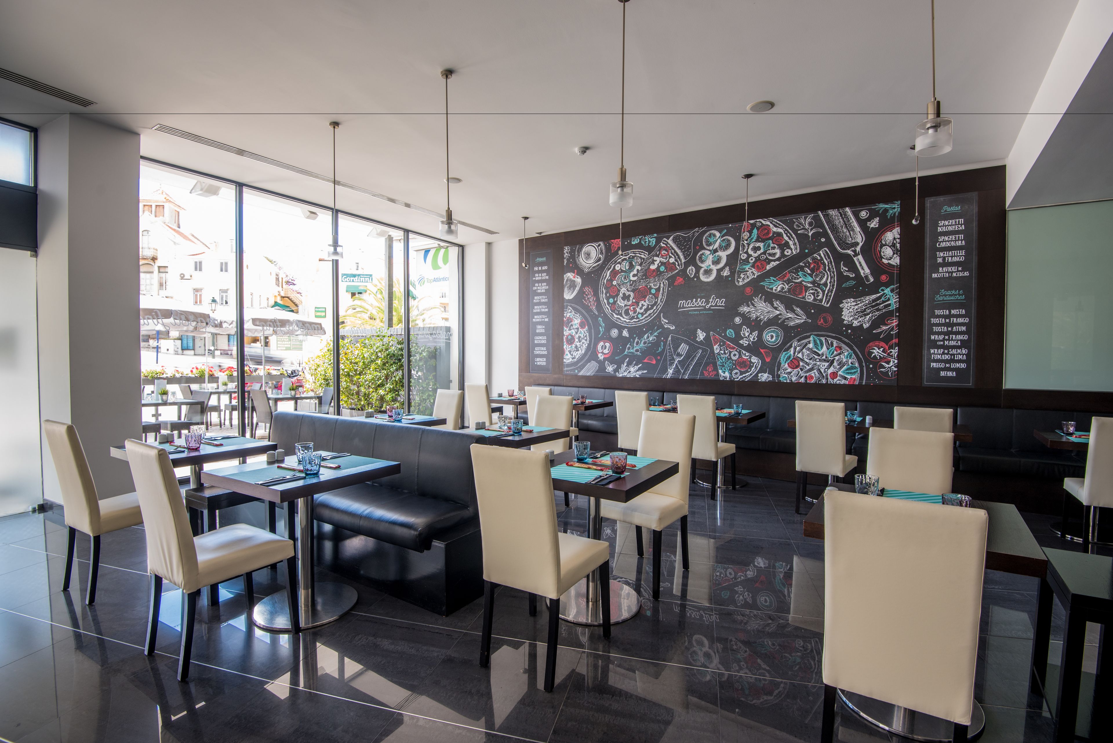 A modern restaurant with a large mural, dining tables, and chairs.