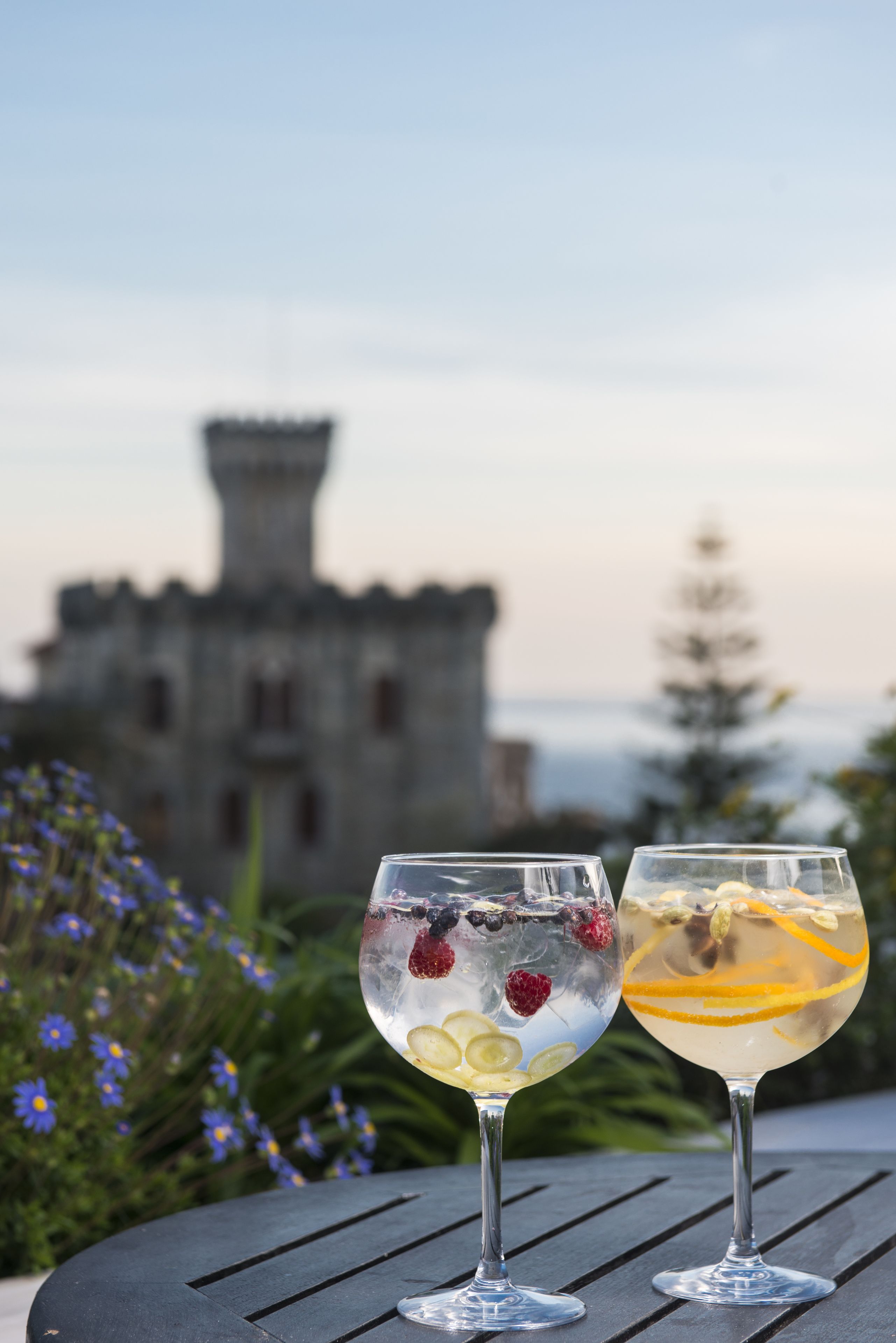 Two glasses of beverages on a table with a castle in the background.