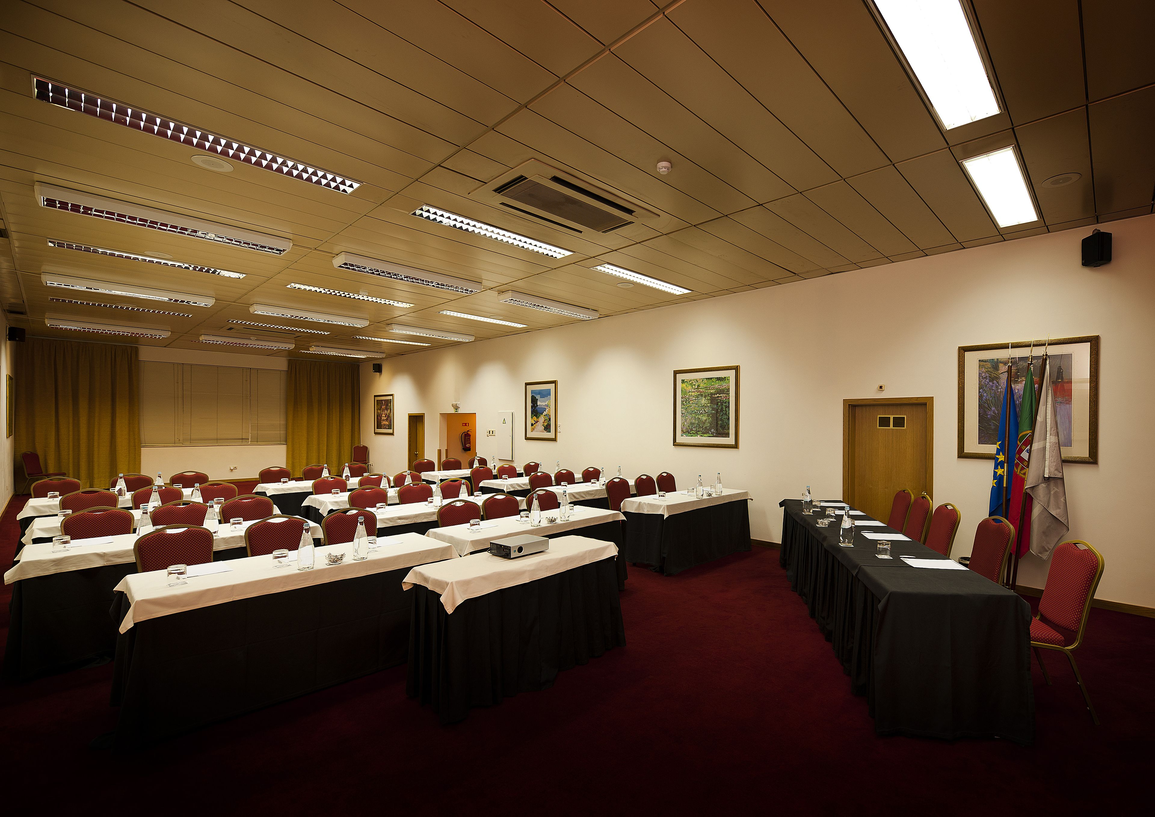 Un salón de conferencias con varias mesas, sillas y banderas.