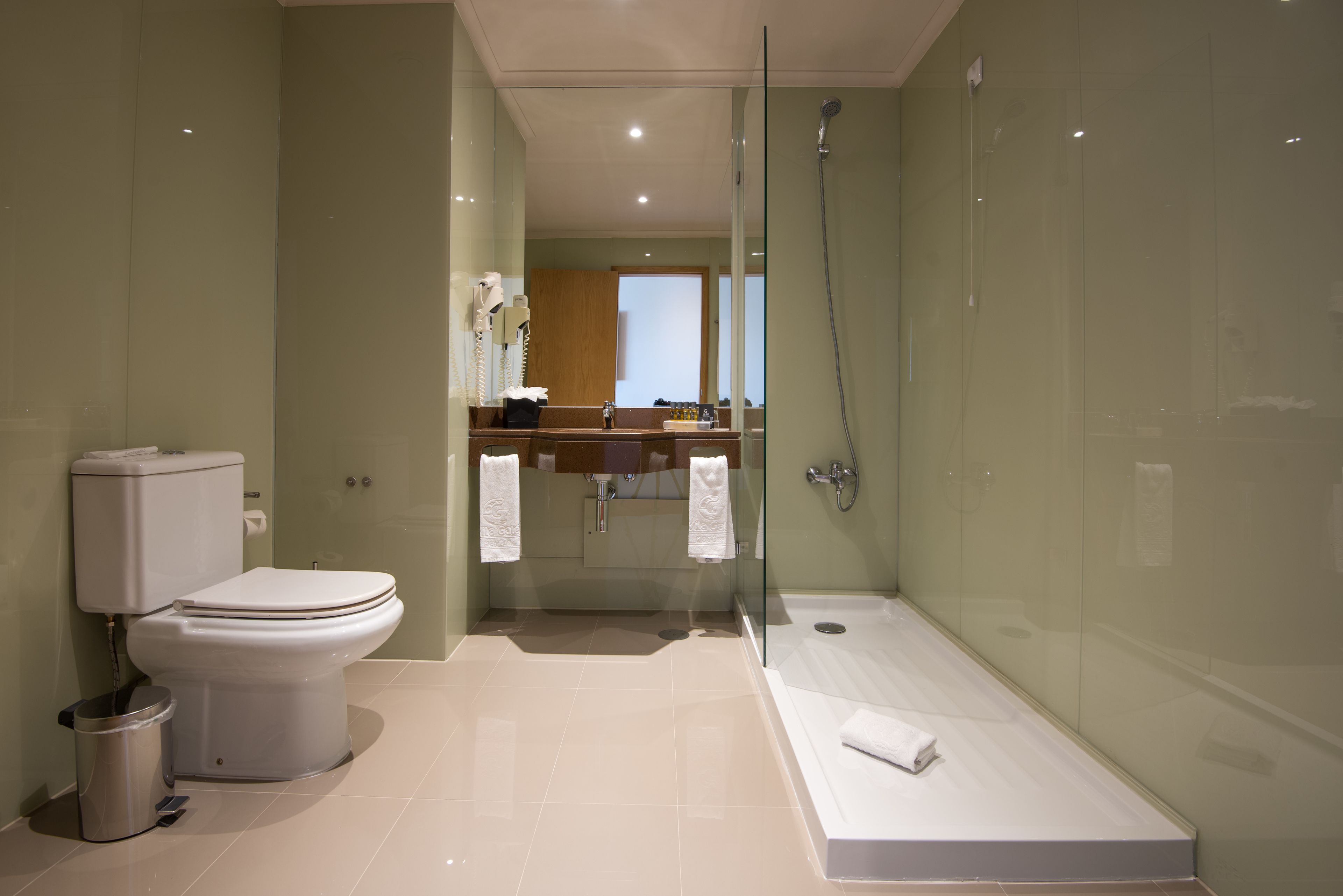 Un baño moderno con inodoro, lavamanos y ducha con mampara de vidrio.