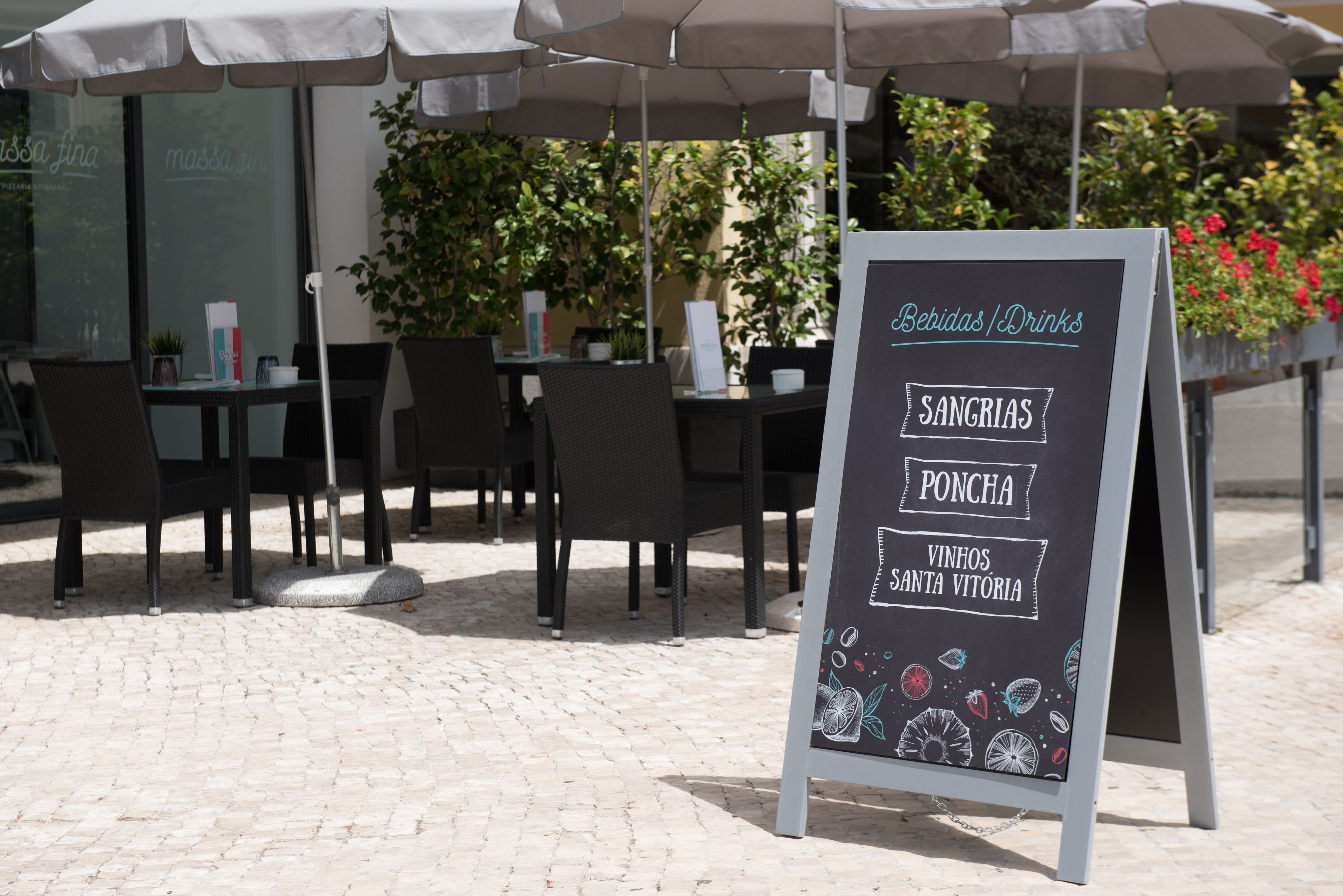 Ein Café im Freien mit Tischen, Stühlen, einer Kreidetafel mit Speisekarte und Blumentöpfen.