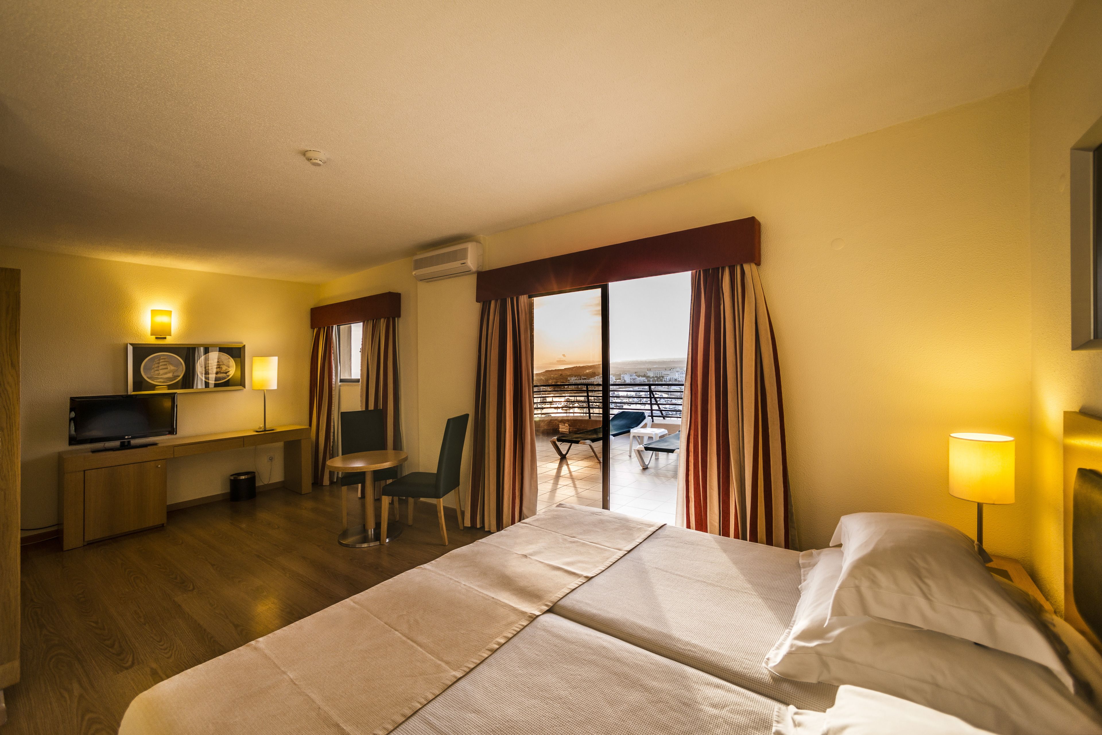 Habitación de hotel con cama, escritorio, silla y vista a la ciudad.