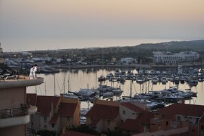 A marina with numerous boats docked, surrounded by buildings with red-tiled roofs.