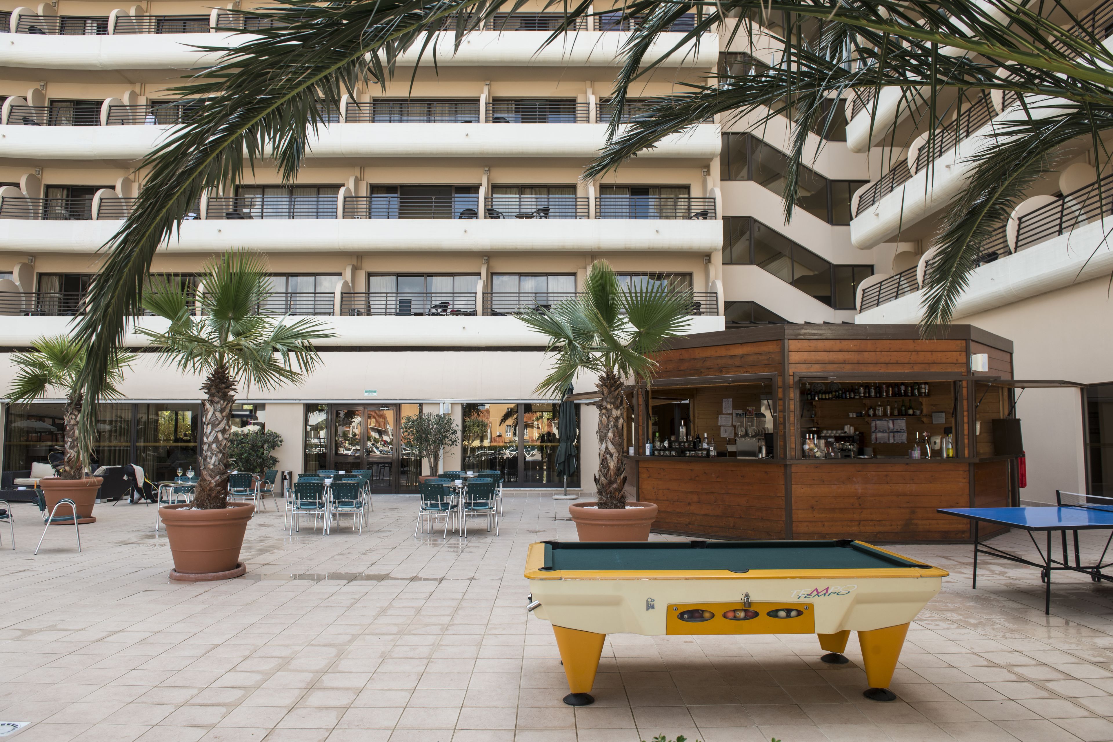 A pool table in an outdoor area with a bar and seating.