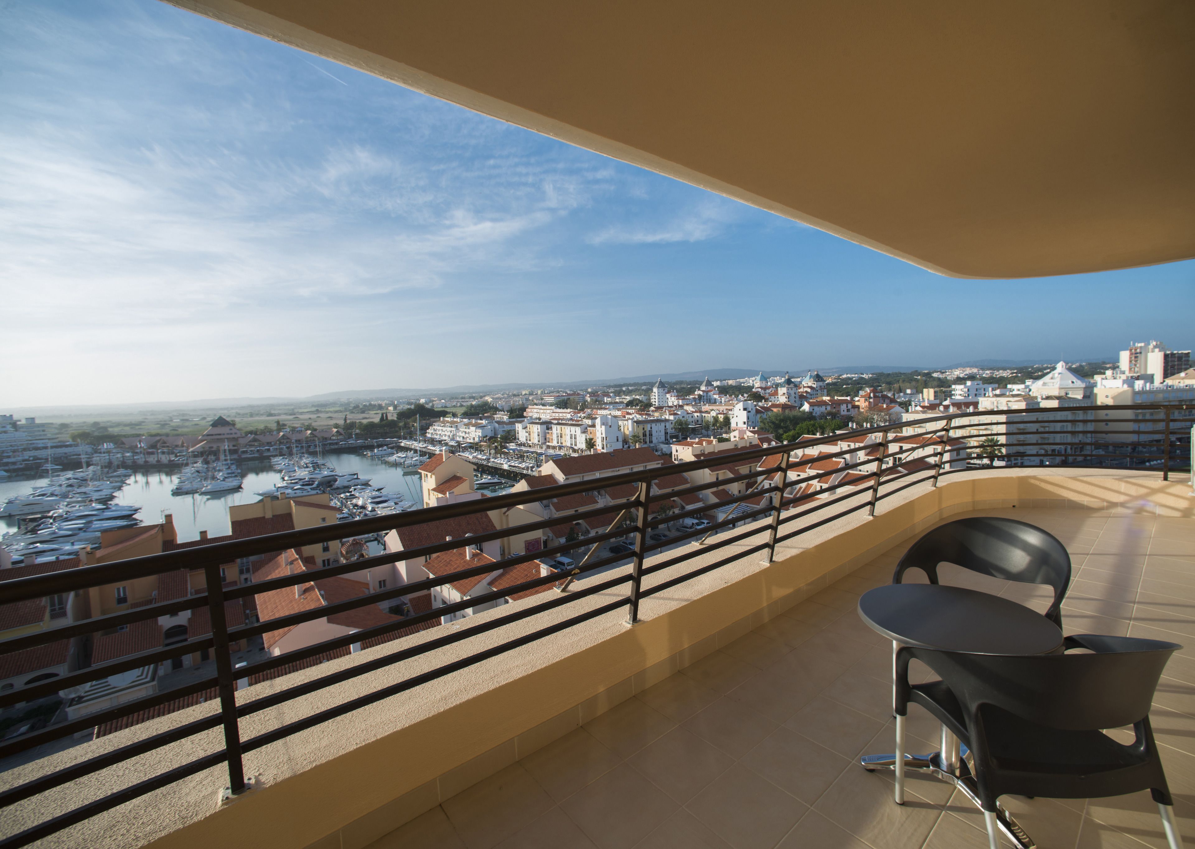 A balcony with a view of a marina and cityscape.
