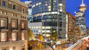 A modern hotel with a curved facade, large windows, and a view of the Space Needle in the background. - Auberge Vancouver Hotel (Vancouver)