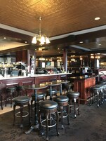 Una zona de bar con varios taburetes y una barra.