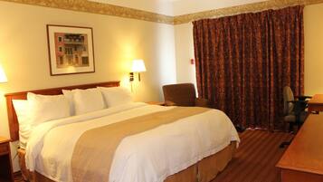 A hotel room with a large bed, a chair, a desk, and a curtain.