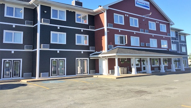 A multi-story hotel with a mix of dark and red exterior walls, large windows, and a covered entrance area.