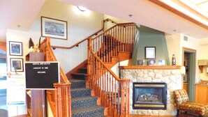 A staircase with wooden railings and carpeted steps leading to a landing.