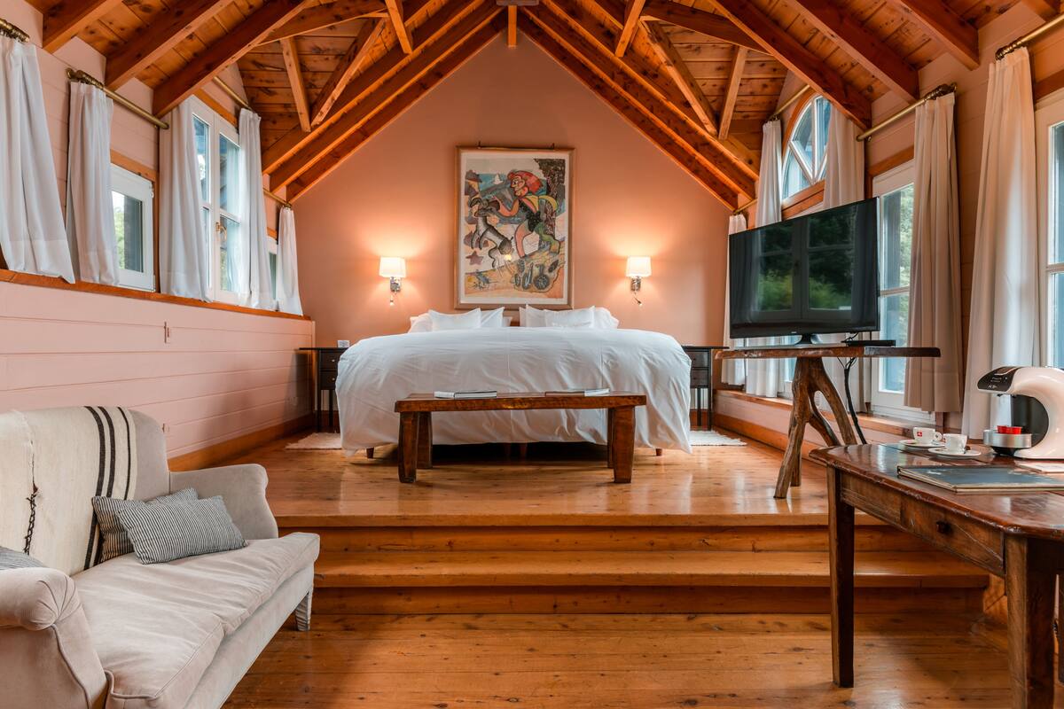 Ein gemütliches Schlafzimmer mit einem großen Bett, einer hölzernen Bank, einem Fernseher und einer Kaffeemaschine.