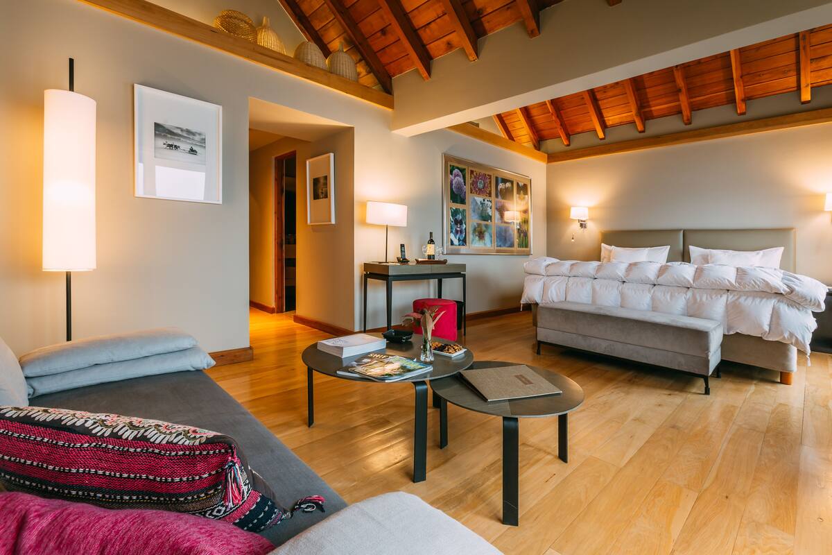 Ein modernes Hotelzimmer mit Bett, Sofa und Couchtisch. An der Wand befinden sich Wandlampen und ein gerahmtes Bild.