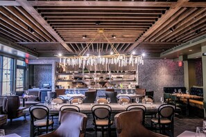 A restaurant with a long dining table, chairs, and a bar area with shelves. - The Burgess Hotel, Atlanta, a Tribute Portfolio Hotel (Atlanta)