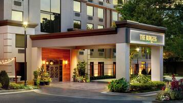 A hotel entrance with a sign reading 'THE BURGESS' and a well-lit driveway.