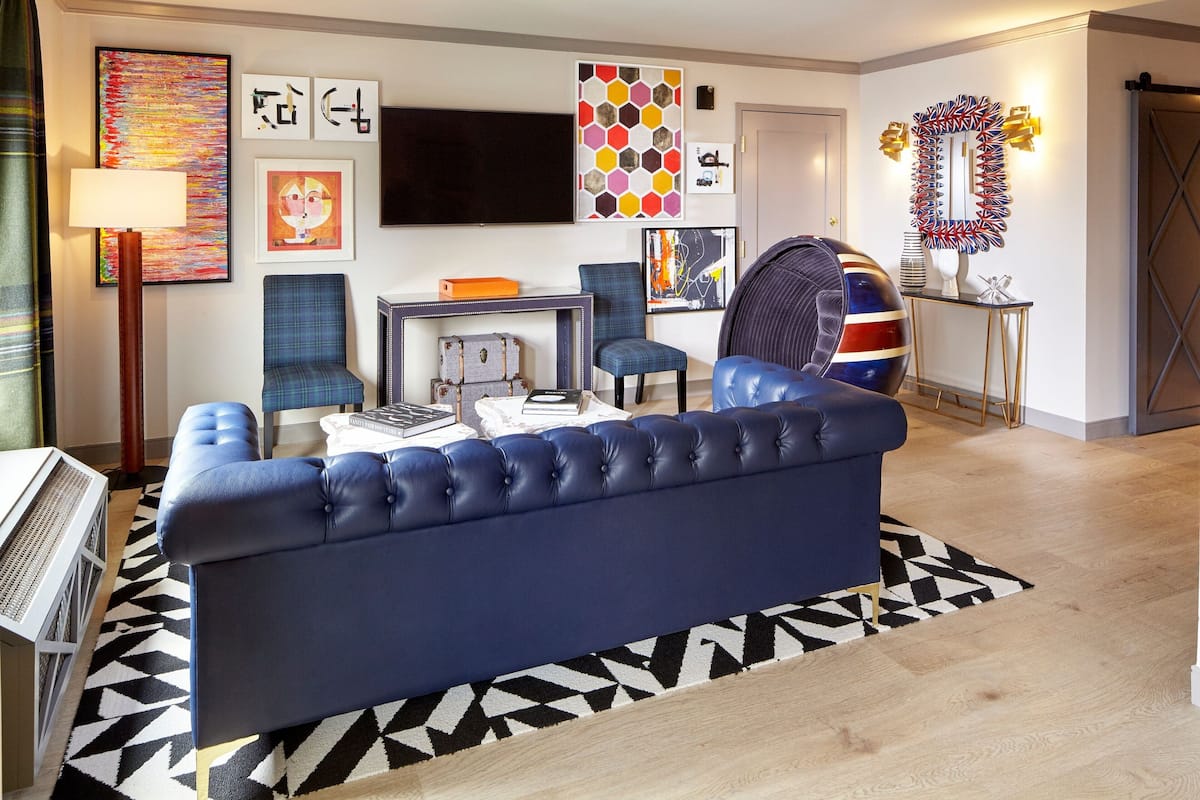 A modern living room with a blue sofa, a flat-screen TV, and various artworks on the walls.
