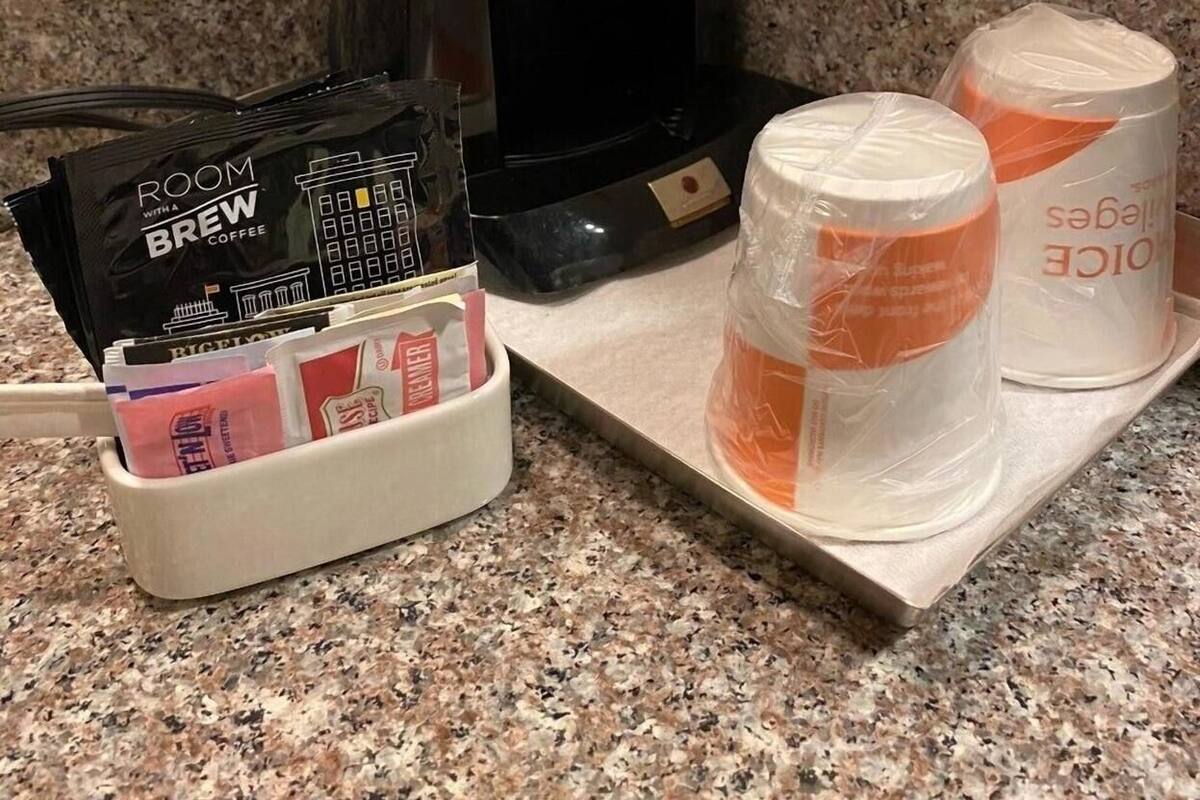 A coffee maker, a coffee pod holder, and two disposable cups on a countertop.
