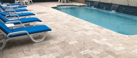 A pool area with lounge chairs and a sign indicating no lifeguard on duty.