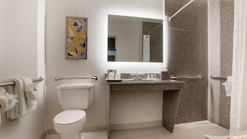 A bathroom with a toilet, a sink, a mirror, and a shower area.
