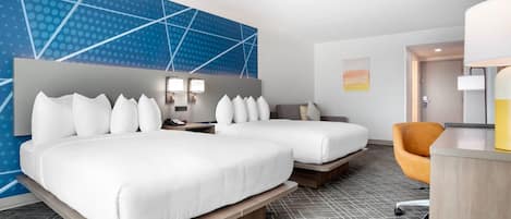 Habitación de hotel con dos camas, un escritorio, una silla y pared de color azul con estampado.