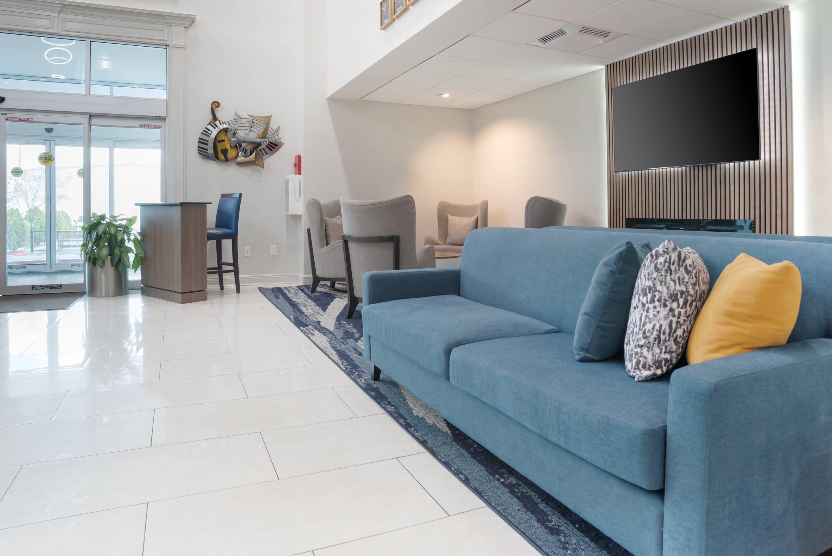 A modern living room with a blue sofa, a flat-screen TV, and a large window.